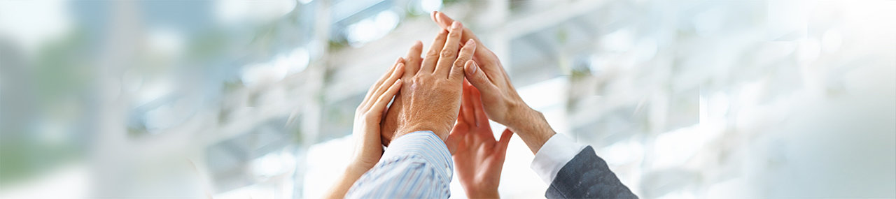 A group of hands from a team high-fiving in an office.
