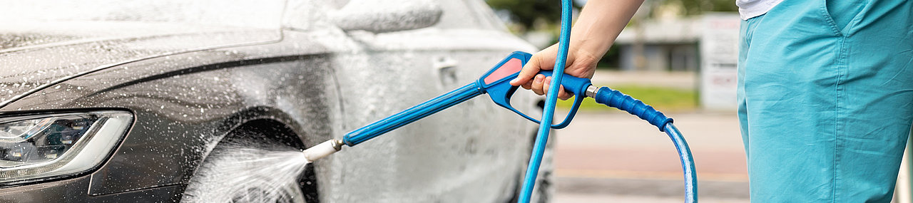 A person out on a sunny summer day washing their car with a Mark VII Jet Wash self serve manual car wash.