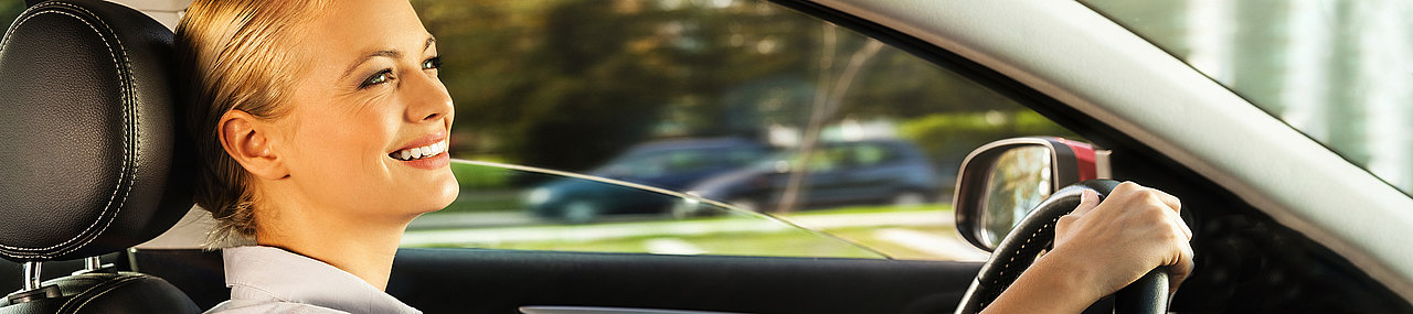 Woman smiling while driving on a sunny summer day.