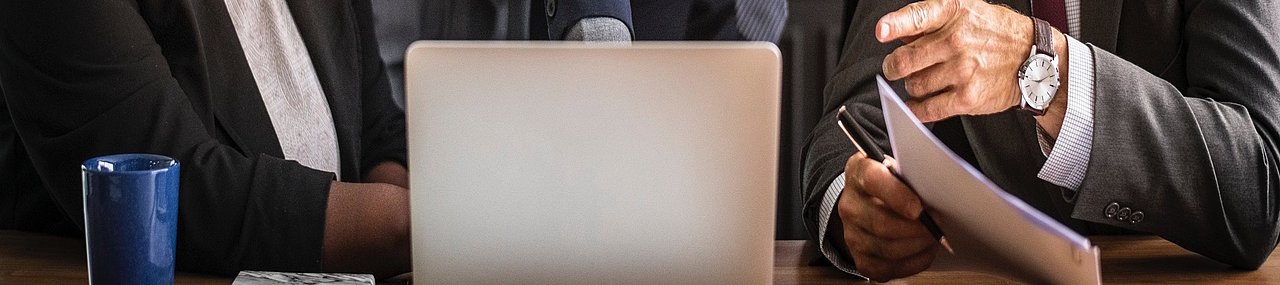 A team meeting around a computer having a discussion.