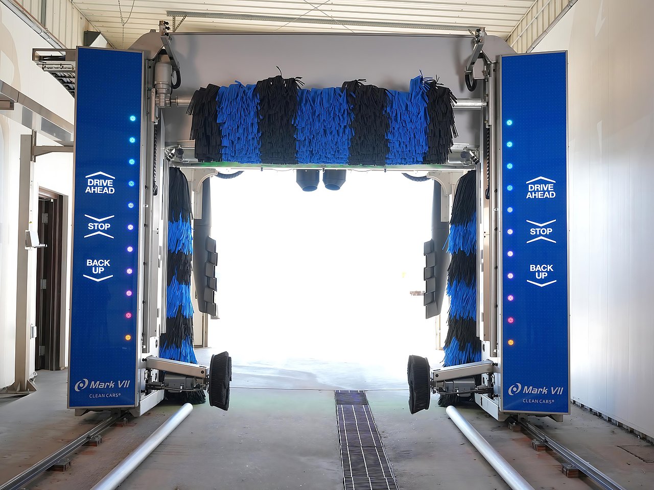 Stainless steel car wash with black and blue striped roll overs above and on the sides. Mark VII ChoiceWash XT provides either a soft-touch or touch-free wash all in one combination machine programed to help you.