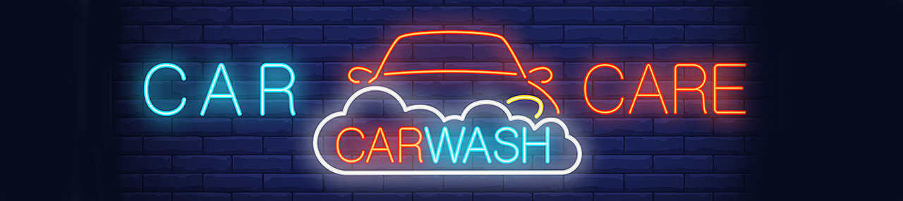 A brick wall with a neon sign of a car getting washed with the words car care car wash. 