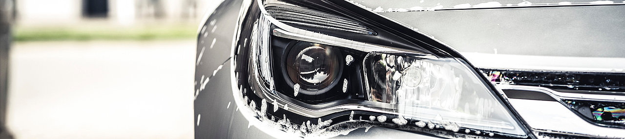 A silver car in a car wash bay on a sunny day.