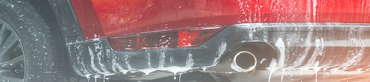 The lower back end of a car dripping water after a wash.