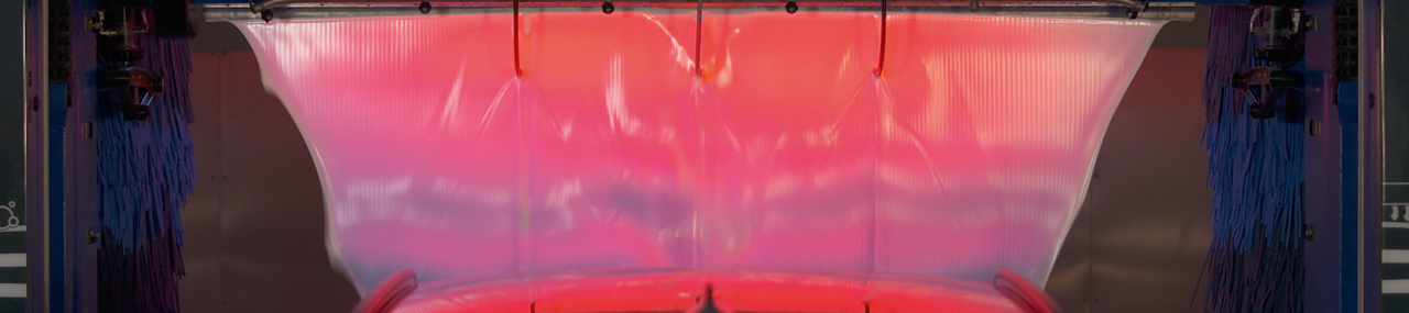 Car in a car wash with the water being lit up by lights.