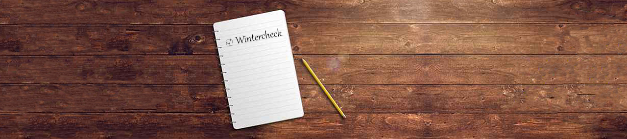 A book on a wooden table with the works "winter check" written next to a box in it.