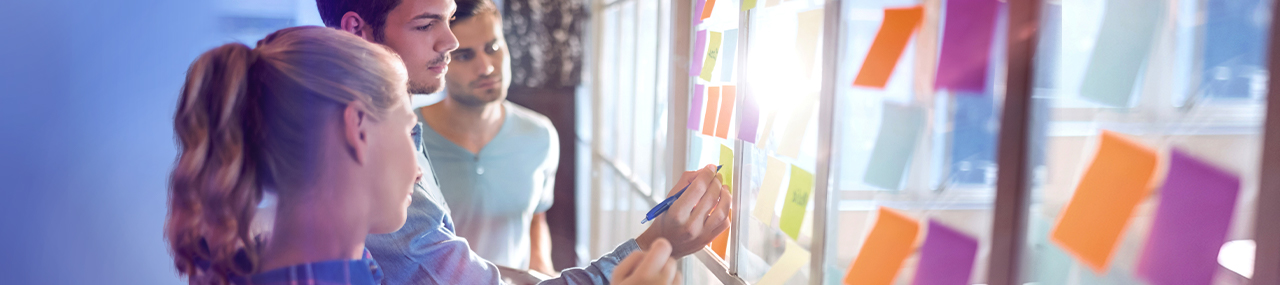 Team writing on post-it notes stuck to a mirror.