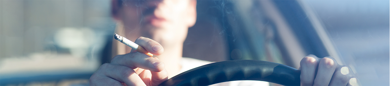 A person smoking a cigarette while driving.